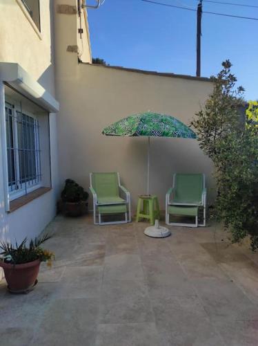 zwei Stühle und ein Regenschirm auf einer Terrasse in der Unterkunft Joli appartement avec cour privé à 150m de la mer in Sanary-sur-Mer