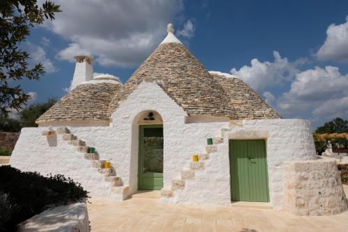 un pequeño edificio blanco con una puerta verde en Dimora Iconica, en Locorotondo