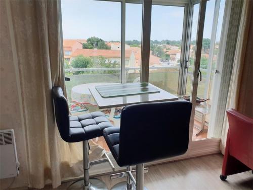 une table et deux chaises devant une grande fenêtre dans l'établissement Studio cosy à 300m de la mer avec parking privatif - Argelès sur Mer - FR-1-388-151, à Argelès-sur-Mer