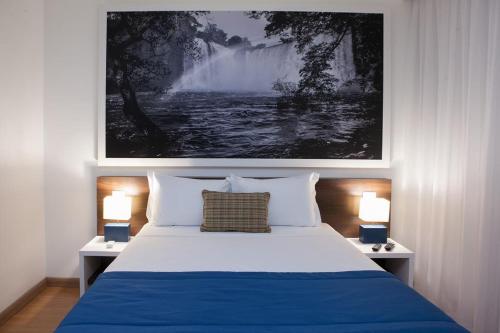 a bedroom with a blue and white bed with two lamps at Golden Tower Aeroporto - Lizz - by Fênix Hotéis in Uberlândia