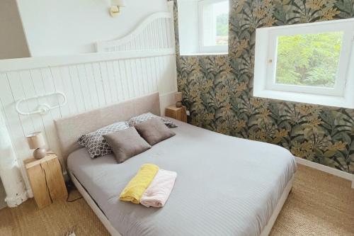 a bedroom with a white bed with two pillows and a window at PILAT - Charmant T2 rénové dans des anciennes écuries in Saint-Galmier