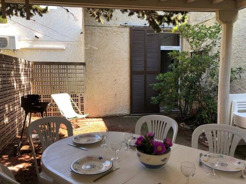 - une table blanche avec des verres et des fleurs sur la terrasse dans l'établissement Villa T4 pour 8 pers. à 350m de la plage avec 3 terrasses, parking privé et équipements complets - FR-1-81-415, à Port-Leucate