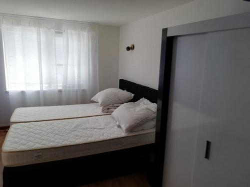 a bedroom with a bed with white sheets and a window at Ferienwohnung mit Meerblick! in Sveti Vlas