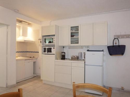 une cuisine avec des armoires blanches et un réfrigérateur blanc dans l'établissement Charmant 2 pièces à 100m de la plage avec jardin, terrasse et activités familiales - FR-1-224B-135, à La Guérinière