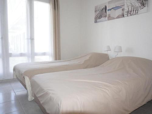 - 2 lits dans une chambre blanche avec fenêtre dans l'établissement Charmant 2 pièces à 100m de la plage avec jardin, terrasse et activités familiales - FR-1-224B-135, à La Guérinière