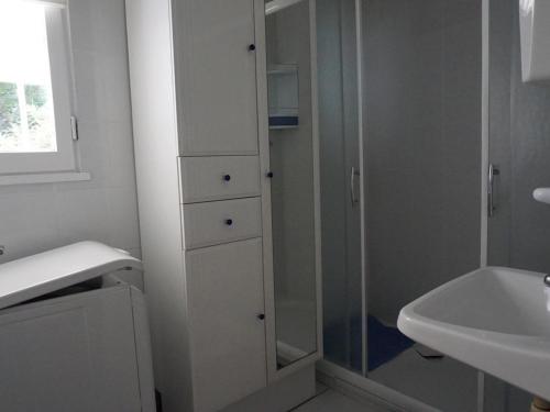 une salle de bain blanche avec une douche et un lavabo dans l'établissement Charmant 2 pièces à 100m de la plage avec jardin, terrasse et activités familiales - FR-1-224B-135, à La Guérinière