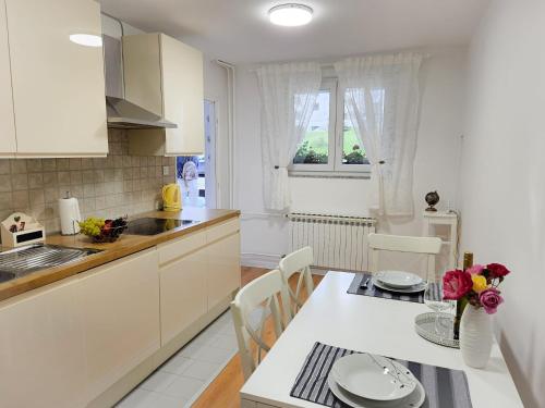 une cuisine avec des placards blancs et une table avec un vase de fleurs dans l'établissement Apartment D&L, aux lacs de Plitvice