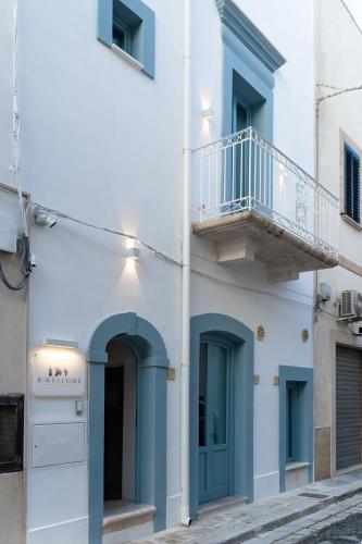 a white building with blue doors and a balcony at B-Welcome Rooms of Charme e Relax in Polignano a Mare