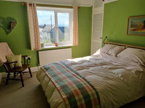 Dormitorio verde con cama y ventana en Cheerful two bedroom cottage in the Forest of Dean en Lydbrook