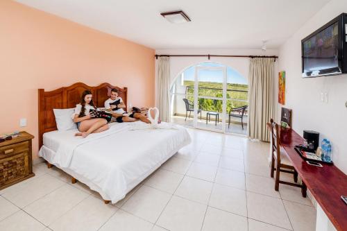 two girls sitting on a bed in a bedroom at Uxmal Resort Maya in Uxmal
