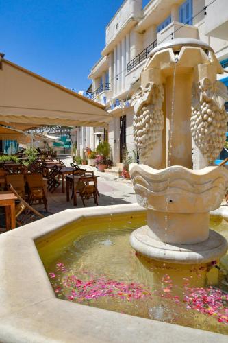 a fountain in front of a hotel with pink flowers at Chariandry Court in Pissouri