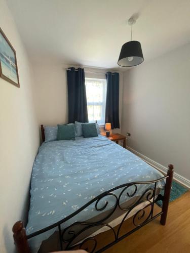 1 dormitorio con cama con sábanas azules y ventana en Hidden Hideout, Cromer, Norfolk, en Cromer