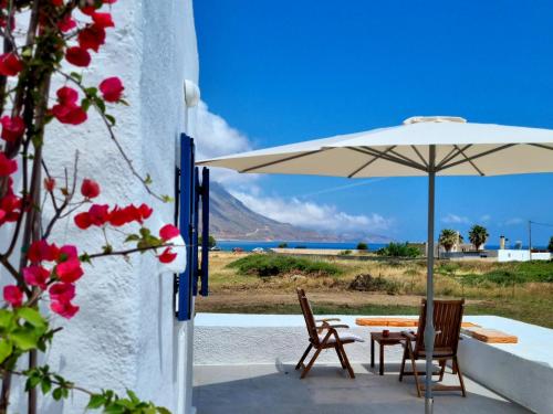 eine Terrasse mit einem Tisch, Stühlen und einem Sonnenschirm in der Unterkunft All Season Lovely Seafront Cottage in Kissamos