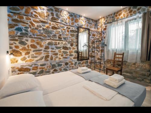 a bedroom with two beds and a stone wall at DreamStone Residence in Skala Prinou