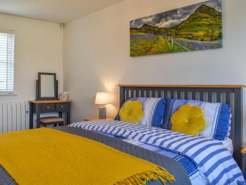 a bedroom with a bed with a yellow blanket at Cosy Cottage in Holker