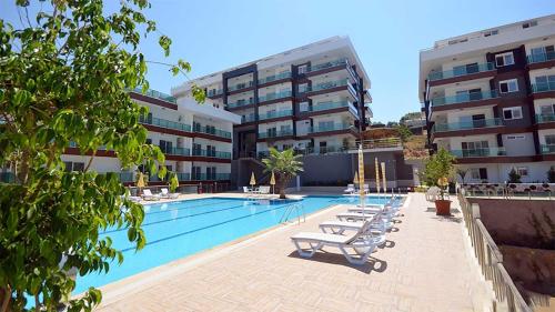 a swimming pool with lounge chairs in front of a building at Spacious Flat at the Beach Pool, huge Balcony, 2 Bedroom in Alanya