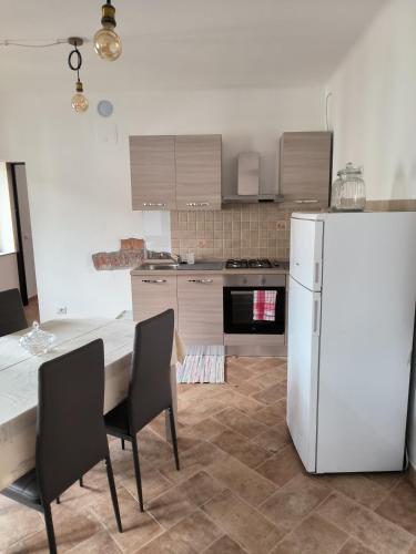 a kitchen with a white refrigerator and a table and chairs at Le stanze del moro house in Pállare