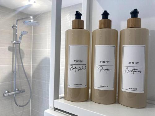 three bottles sitting on a shelf in a bathroom at Robins Nest Luxury Bungalow in Northampton