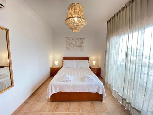 a bedroom with a bed and a large window at Aloha Burgau Guesthouse in Burgau