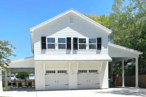 une maison blanche avec deux portes de garage dans l'établissement Vacation Rental in Old Town Bay St Louis plus parking for RV, à Bay Saint Louis
