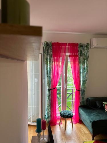a living room with pink curtains in front of a window at Apartman AURORA CETINJE in Cetinje