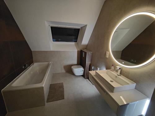 y baño con lavabo, bañera y espejo. en Appartement 48m², Strasbourg centre à 15 min en train, en Fegersheim
