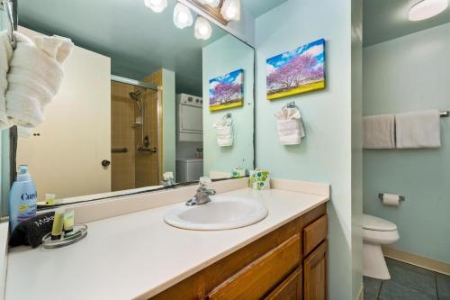 a bathroom with a sink and a mirror and a toilet at Hawaiian-Style Oceanview Across the Street from Historic Magic Sands Beach Park - White Sands Village 202 in Kailua-Kona