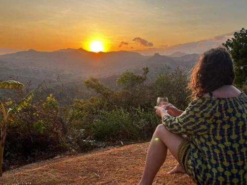 a woman sitting on a hill taking a picture of the sunset at Hawk's Nest Bed & Breakfast in La Laguna de San Carlos