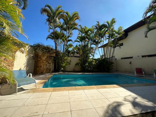 a swimming pool in front of a house with palm trees at Casa Jardim das Colinas in São José dos Campos