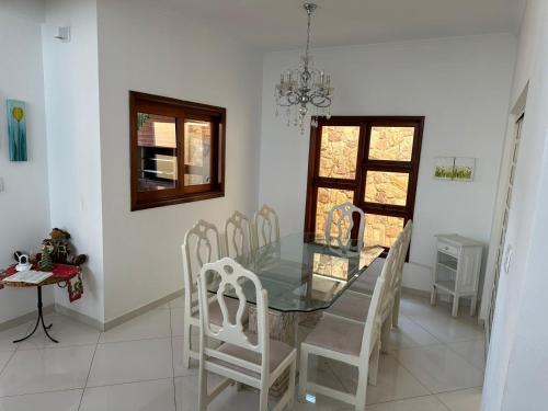 une salle à manger avec une table en verre et des chaises blanches dans l'établissement Casa Jardim das Colinas, à São José dos Campos