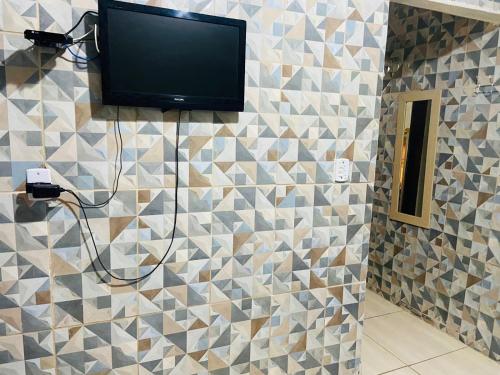 a television on a tiled wall in a bathroom at Pousada Familia Aparecida in Aparecida
