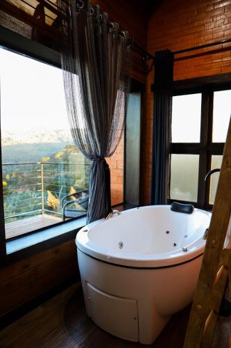 a large bath tub in a room with windows at Infinity Valley Cabanas de Altitude Urubici in Urubici