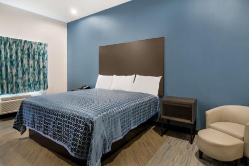 a hotel room with a bed and a chair at Scottish Inns- Forest Hill in Forest Hill