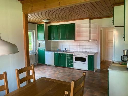 una cocina con armarios verdes y una mesa. en Ta det lugnt en Råda