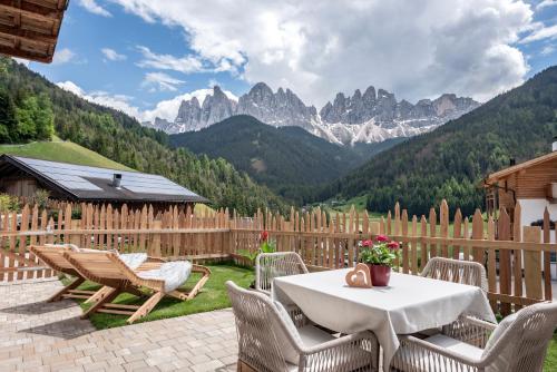 a patio with a table and chairs and mountains at Oberkantiolhof in Villnoss