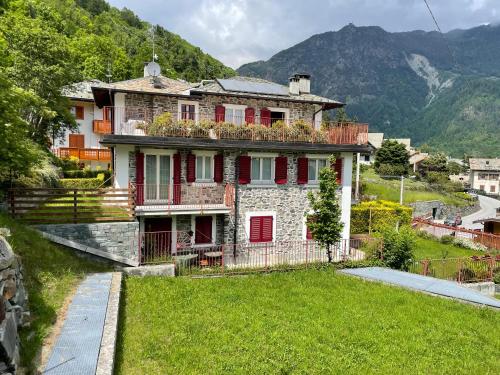 an old house with red shutters on a hill at Villa Irma in Chiesa in Valmalenco