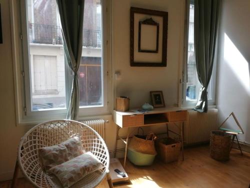 Zimmer mit einem Stuhl, einem Schreibtisch und Fenstern in der Unterkunft Chez mamie framboise centre ville avec courette in Dieppe