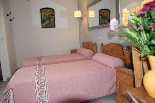 une chambre avec deux lits avec des draps roses et un vase de fleurs dans l'établissement Villa Isaline, appartement Cyclamens T1 bis-parking privé, à Aix-les-Bains
