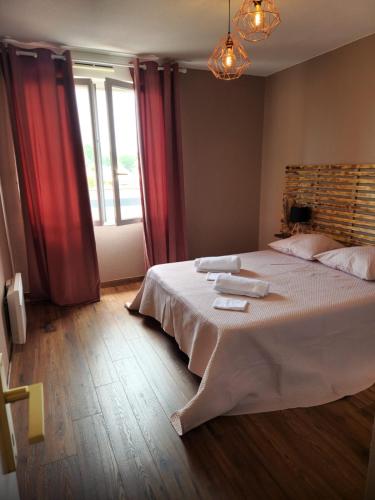 - une chambre avec un grand lit et des rideaux rouges dans l'établissement Logis Gaïa, à Labenne