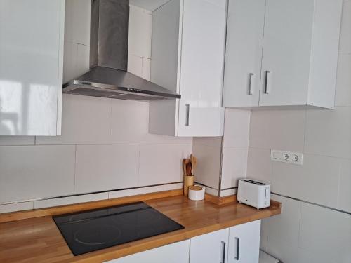 a kitchen with white cabinets and a wooden counter top at Ático con terraza in Cieza