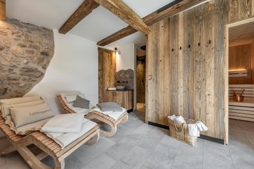 Habitación con 2 sillas de mimbre y pared de piedra. en Oberkantiolhof en Villnoss