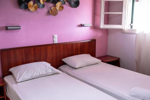 two twin beds in a room with pink walls at Katerina Studios & Apartments in Sidari