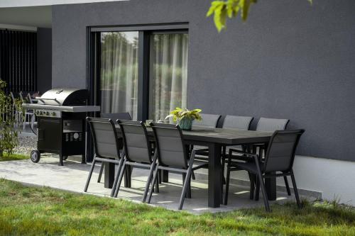 a dining table and chairs with a grill in a backyard at Capsula Luxury Apartment Umag in Umag