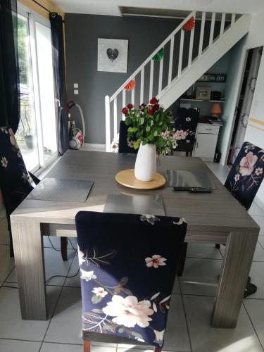 una mesa de comedor con un jarrón de flores. en VILLA DU BIEN ËTRE, en Argenton-sur-Creuse