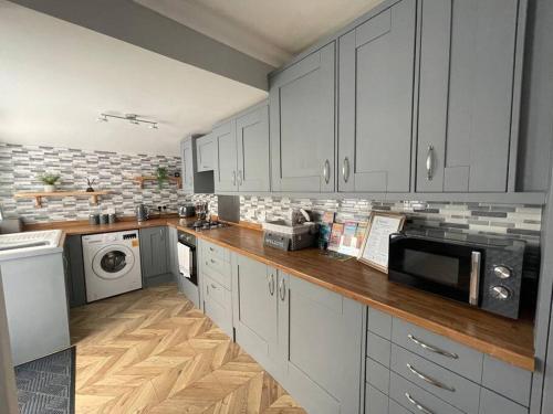 a large kitchen with white cabinets and a microwave at Taylor’s Retreat in Radipole