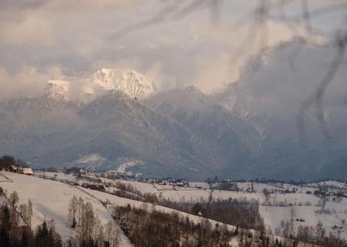 a snow covered mountain range with a town in the foreground w obiekcie IKI Retreat Magura w mieście Măgura