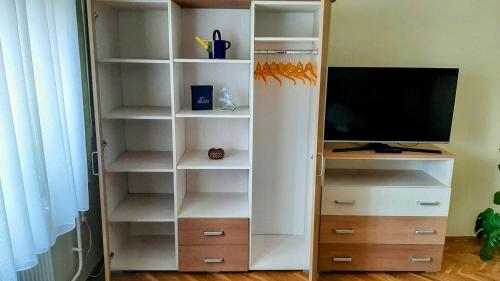 ein weißes Bücherregal mit einem TV und einem TV in der Unterkunft MIMO APARTMAN in Hajdúszoboszló