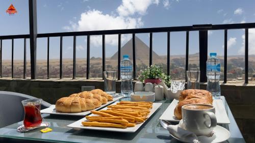 a table with two plates of food and drinks on it at Pyramids Tower view inn in Nazlat as Sammān