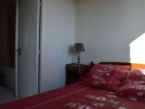- une chambre avec un lit doté de draps rouges et d'une lampe dans l'établissement Appartement 2 pièces avec parking, terrasses, animaux admis à 100m de la plage - FR-1-225D-10, à Saint Cyprien Plage