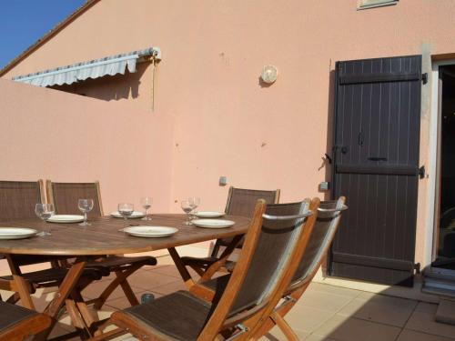 - une table et des chaises en bois avec des verres à vin dans l'établissement Appartement 2 pièces avec parking, terrasses, animaux admis à 100m de la plage - FR-1-225D-10, à Saint Cyprien Plage